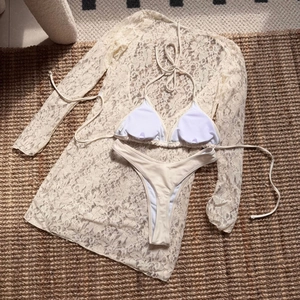 Detailed flat lay of cream three-piece lace bikini set with long sleeve cover-up