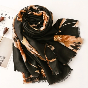 Close-up of black cotton-linen scarf with gold leaf print and frayed tassel edges