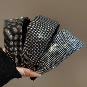 Detail view of a wide rhinestone headband showing sparkling black and silver crystals