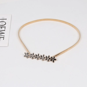 Detailed shot of golden elastic metal belt with six black enamel flower charms buckle