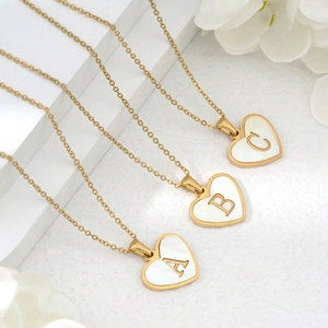 Detailed macro view of heart-shaped gold pendants with white shell inlay for necklace