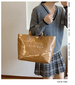 Brown gloss tote bag featuring white lettering shown with a pleated skirt outfit