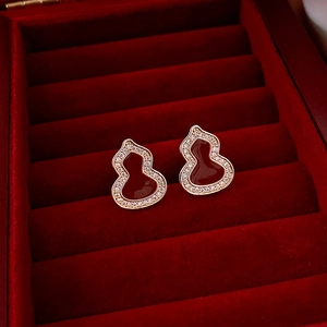 Vue détaillée des boucles d'oreilles gourde rouge avec bordure dorée et zircons
