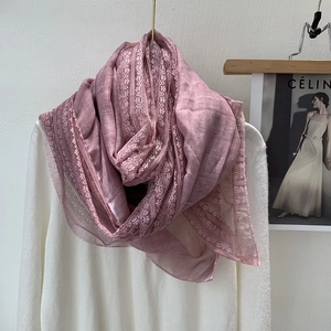 Close-up of pink linen-cotton scarf featuring intricate lace details and fringe