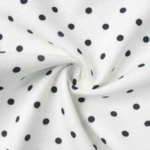 Vue macro du tissu à pois montrant le drapé doux et l'imprimé blanc et noir élégant