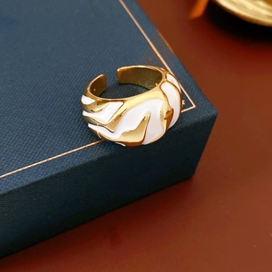 Detail view of gold wave ring with white enamel finish on a blue jewelry box rim