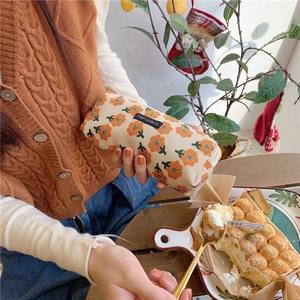 Detail view of corduroy floral stationery pouch with woven label in cozy setting
