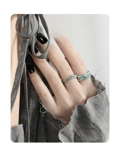 Detailed view of silver textured rings with turquoise enamel inlay on model with dark nails
