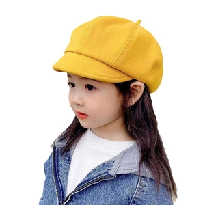Bright yellow kids beret hat worn by a child in denim jacket against white background