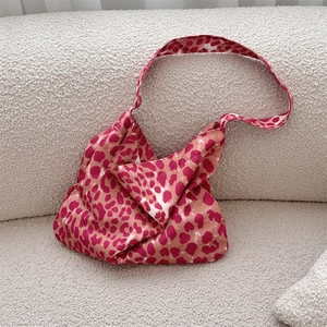 Detail of soft leopard print canvas shoulder bag resting on a white plush surface