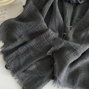 Detailed close-up of dark grey cotton linen scarf with raw fringe edges and crinkled texture