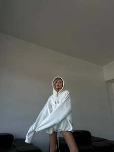 Detail of white oversized hoodie with black UKRAI lettering and drop shoulder design