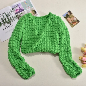 Detail of green long sleeve crop top with textured bubble fabric and drawstring front