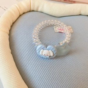 Détail d'un chouchou spirale bleu avec des breloques mignonnes en forme de cœur et d'étoile
