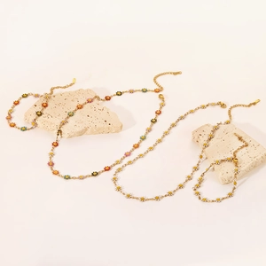 Detalle de collares y pulseras de titanio de 18K con dijes de margaritas de colores vivos