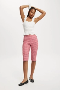 Full view of women's red plaid cropped pants styled with a white ruffled tank top