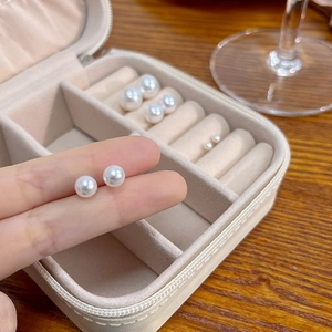 Close-up of elegant white pearl stud earrings in three sizes on a jewelry organizer