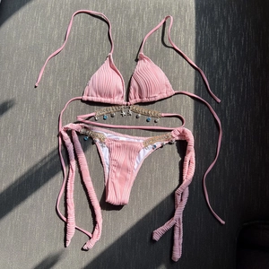 Detail of pink ribbed bikini with metal chains and starfish shell pendants