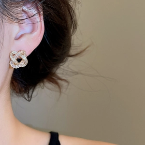 Detail of gold-plated silver needle earrings with cubic zirconia on a model's ear
