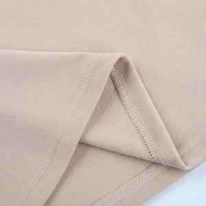Detailed macro view of high-quality stitching and knit texture on beige dress hemline