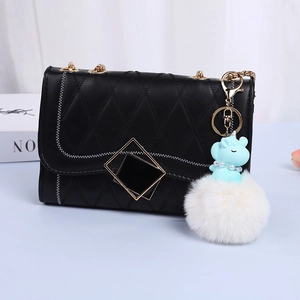 Quilted black shoulder bag with gold chain, blue unicorn, and white pom-pom charm