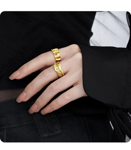 Detail of irregular brushed gold rings and wave band with micro-set zircons on hand