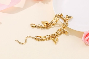 Detail of gold double-layered heart charm bracelet on an elegant aesthetic background