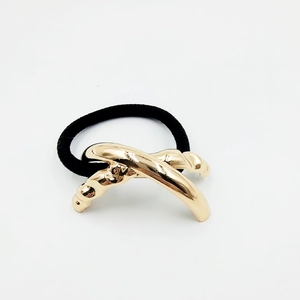 Macro detail of elegant gold X-shaped alloy charm on black elastic ponytail hair tie