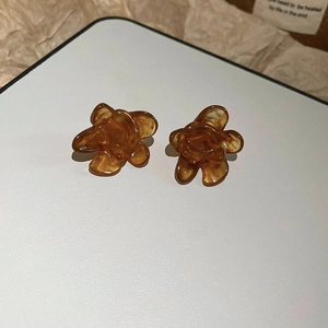 Macro shot of amber resin flower earrings on rustic paper showing fine petals and gloss