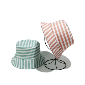 Chapeaux de soleil rayés en toile vert menthe et rose saumon sur un support minimal