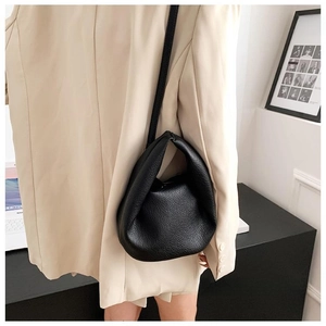 Detail view of black lychee grain leather handbag with soft pleated cloud bag design