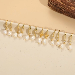 Close-up of elegant freshwater pearl earrings with gold hooks and zircon accents