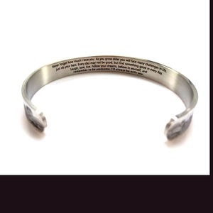Macro view of brushed stainless steel cuff with engraved inspirational quote inside