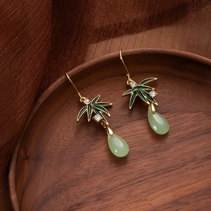 Detailed view of bamboo-leaf earrings with green enamel and teardrop faux jade tassels