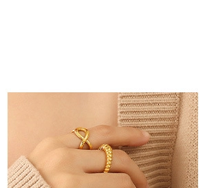 Close-up of golden croissant ring and twisted rope ring worn over beige knitwear