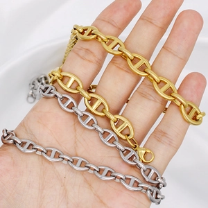 Detailed view of handmade stainless steel anchor chain necklaces held in a palm