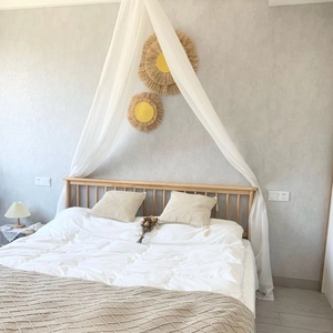 Detail of bohemian raffia wall decor in a warm bedroom setting with white canopy