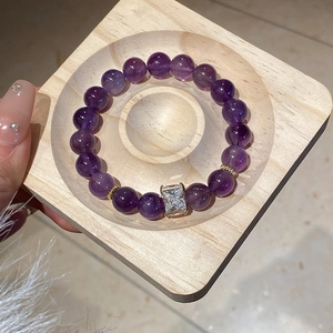 Detail of purple amethyst beaded bracelet with silver zircon stone on wooden tray