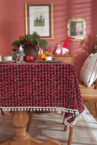 Detail of red and black checkered Christmas tablecloth with white snowflake patterns and pompom fringe