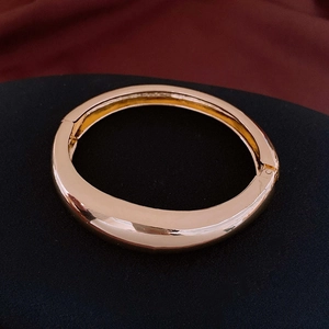 Gros plan d'un bracelet large doré en métal poli avec mécanisme d'ouverture à charnière