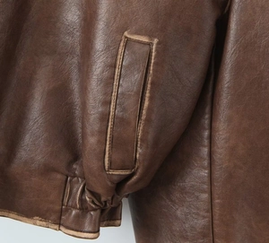 Gros plan sur la veste en similicuir marron montrant la texture et les coutures nettes