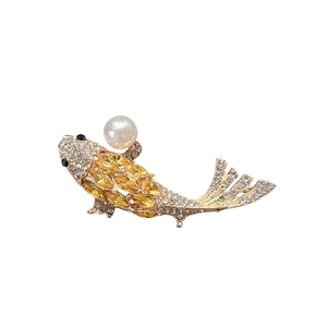 Elegant gold koi fish brooch with yellow crystals and a white pearl on white background