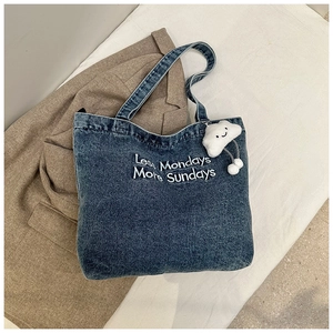 Détail du sac cabas en jean bleu foncé avec broderie et charm nuage peluche