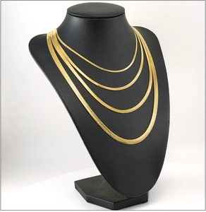 Detail of four different widths of 18K gold plated herringbone chains on a black bust