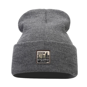 Dark grey knitted beanie with vintage leather patch on white background for men and women