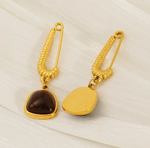 Detail view of 18K gold-plated safety pin earrings with square brown natural stones