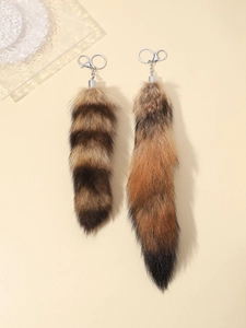 Detail of two faux fur animal tail keychains with silver metal spring rings