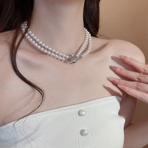 Detail of a double-layer pearl necklace with a shimmering zircon Saturn orb pendant
