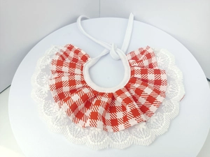 Detail of red and white plaid pet bib with intricate white lace trim and drawstring tie