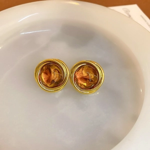 Close-up of vintage golden round earrings with amber resin texture in a white tray